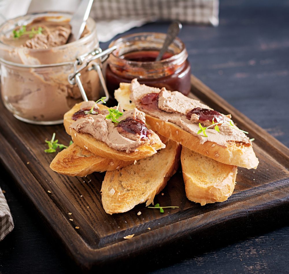 Chicken homemade liver paste or pate in glass jar with toasts and lingonberry jam with chili. Copy space